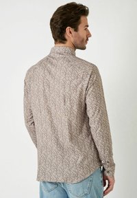 Lange mouwenshirt in lichtbruin met een paisleypatroon. Gemaakt van katoen, met een standaard kraag en knoopmanchetten. Soepele textuur.