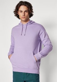 Felpa lilla con tasca frontale, cappuccio con cordino e polsini a costine. Realizzata in tessuto morbido con una superficie liscia. Vestibilità casual.