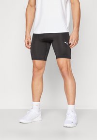 Čierne športové šortky vyrobené z elastického materiálu, so strihom do polovice stehna, priliehavým dizajnom a malým bielym logom Puma na boku.
