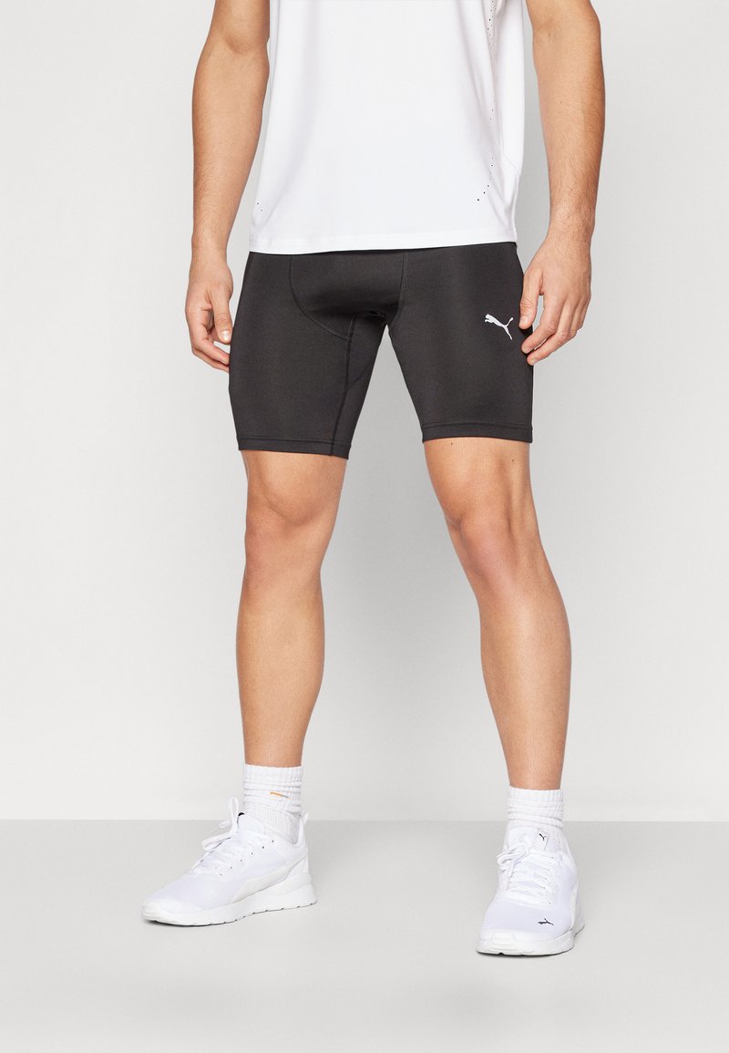Shorts de sport noirs en matériau extensible, avec une coupe mi-cuisse, un design ajusté et un petit logo Puma blanc sur le côté.