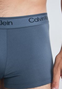 Graue Baumwollmischung Boxershorts mit einem kontrastierenden Bund und "Calvin Klein" Logo. Glatte Textur, enganliegendes Design und kurze Beinlänge.