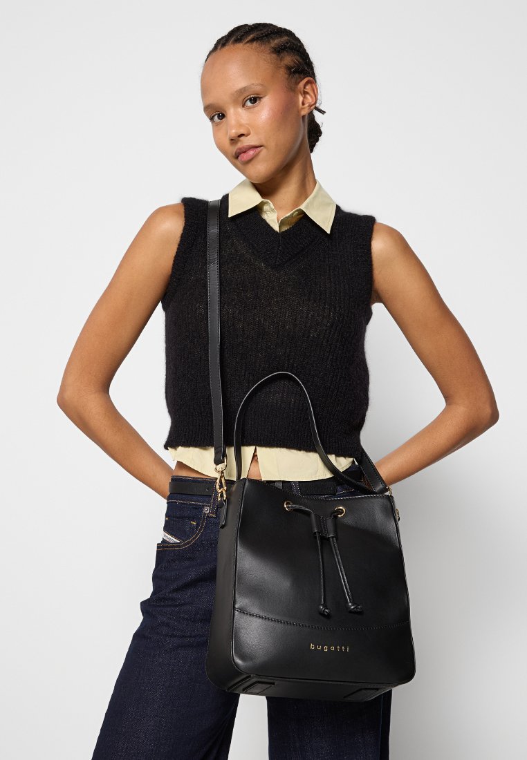 Borsa a secchiello in pelle nera con hardware dorato, chiusura a cordoncino e base piatta. Superficie testurizzata, design semplice e logo sulla parte anteriore.