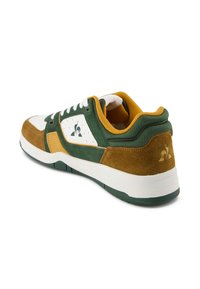 Sneaker verde e marrone con punta bianca, materiali in suede e tessuto, collo imbottito e dettaglio del logo sul lato e sul tallone.