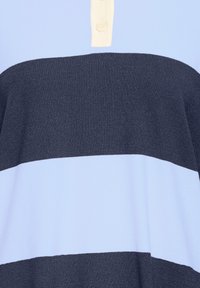 Mėlynas polo marškinėlis su tamsiai mėlynomis horizontaliomis juostelėmis, kreminėmis sagų juostelėmis ir švelnia mezginio tekstūra.