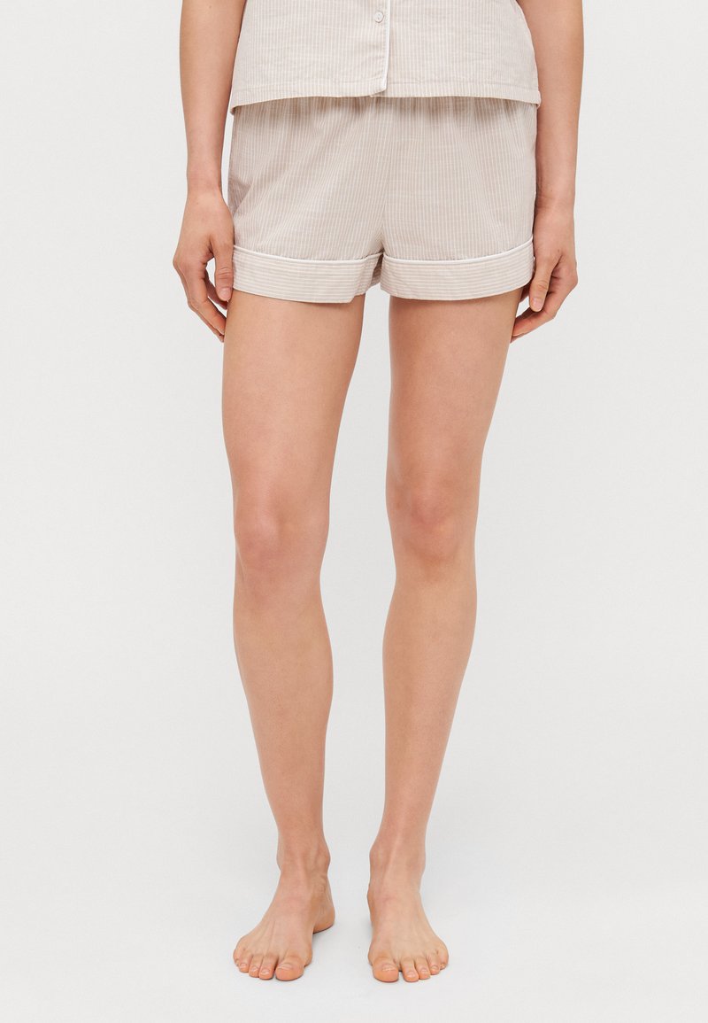 Lichtbeige pyjamashorts met dunne verticale strepen, zachte stof, opgerolde zoom en een elastische tailleband voor comfort. Gecombineerd met een bijpassend topje.