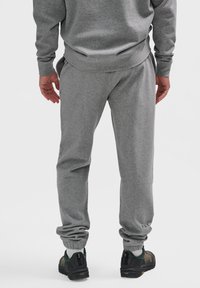 Graue Jogginghose aus weichem Material, mit elastischen Bündchen, seitlichen Taschen und einem kleinen Logodetail am Saum.
