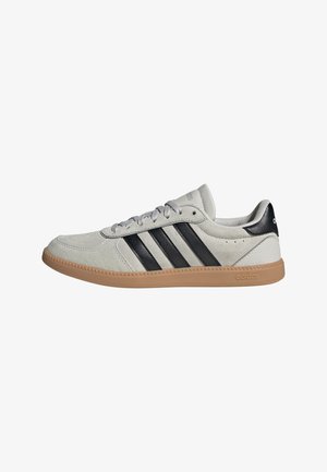 Light gray suede sneakers with black leather accents and three black stripes. Rubber gum sole and gray laces. Minimalist design.