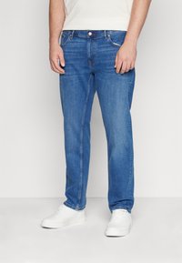Blå denimjeans med rakt ben, som har subtila blekningar, klassisk femficksdesign och knappgylf.