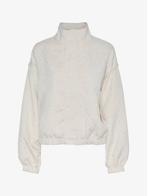 Veste blanche matelassée avec un col montant, des épaules tombantes et des poignets élastiques. Dotée de poches latérales et d'un motif floral texturé.