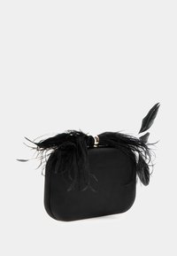 Juodas delninukas su lygia paviršiumi, apvalia forma ir auksiniais akcentais. Sukurtas su juodais plunksnomis, pabrėžiančiomis uždarymo vietą.