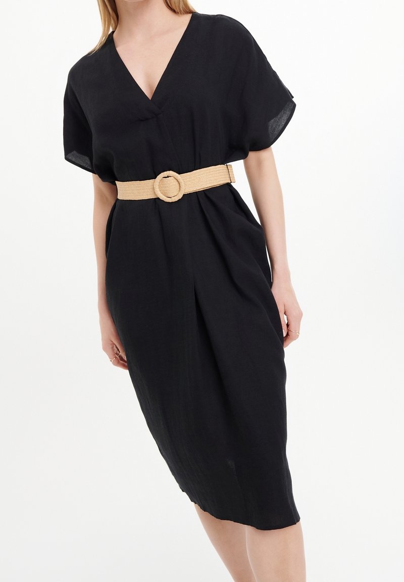 Schwarzes Leinenkleid mit V-Ausschnitt, kurzen Ärmeln und einer taillierten Taille, die durch einen gewebten beigen Gürtel mit runder Schnalle betont wird. Mittellanges Design.