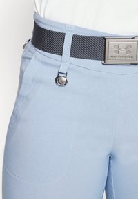 Hellblaue Hose mit schickem Design, ausgestattet mit einem schwarzen, strukturierten Gürtel und silberfarbenen Hardware-Akzenten. Detaillierte Nähte an den Taschen.
