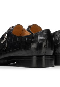 Schwarze Lederschuhe mit Krokodilstruktur, rundem Zehenbereich und mittelhohem Absatz. Verfügen über ein silberfarbenes Metallakzent an einem Riemen.