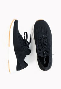 Black athletic shoes with a knit upper, featuring a textured design, white midsole, and gum rubber outsole. Laces are tied.
