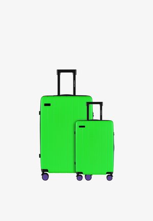 Zwei grüne Hartschalenkoffer, einer groß und einer klein, mit vertikalen Rillen, schwarzen Teleskopgriffen und lila Rädern.