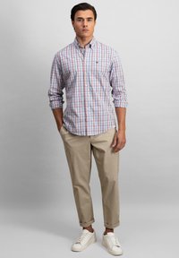 Geruite button-down shirt in rood, blauw en wit; beige broek; witte sneakers; stof lijkt soepel met een casually fit.