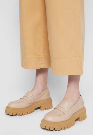 Mocassini in pelle beige con una spessa suola in gomma a rilievo. Il design presenta una finitura liscia e dettagli cuciti sulla tomaia.