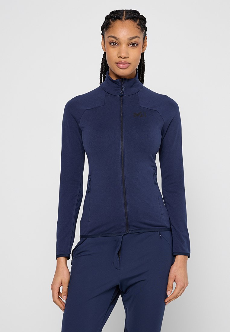Giacca zip-up blu navy realizzata in tessuto liscio e elastico con colletto alto, dotata di tasche laterali e di un logo minimalista sul petto.