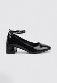 Chaussure noire en cuir vernissé avec un talon carré, bout pointu, bride de cheville et texture brillante. Présente un talon carré de hauteur intermédiaire pour plus de stabilité.