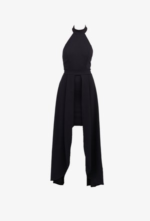 Black halter dress featuring a fitted bodice, high neckline, and flowing skirt with asymmetric hem. Made from smooth, stretchy fabric.