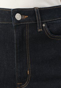 Dunkelblaue Jeans aus Denim mit orangefarbenen Nähten, silberner Knopfverschluss und Fronttaschen. Bieten eine glatte Oberfläche und ein klassisches Fünf-Taschen-Design.