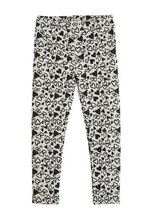 Sorte og hvide leggins med et gennemgående hjerte-mønster på en lys grå baggrund, lavet af et blødt, strækbart stof.