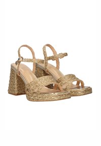 Sandalias con tiras trenzadas doradas y un tacón grueso tejido. Interior de cuero suave y correa ajustable en el tobillo para un ajuste seguro.