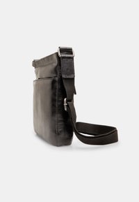 Borsa a tracolla in pelle nera con finitura opaca, caratterizzata da una forma piatta, cinturino in tessuto regolabile e compartimento principale con zip.