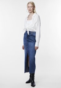 Fehér, hosszú ujjú ing, derékra kötve, kék farmer szoknyával, amely elöl hasítékkal rendelkezik, és fekete bokacsizmával párosítva. Összességében sima textúrák.