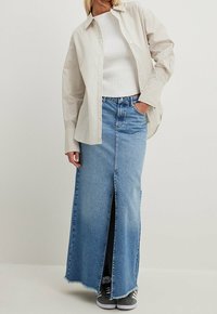 Lätt randig skjorta med knappar över en ribbad vit topp, kombinerad med en högmidjad blå denim maxikjol med slits fram och fransad fåll.