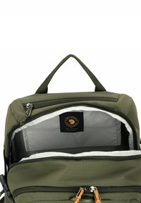 Grüner Rucksack aus strukturiertem Stoff mit zwei Reißverschlussfächern und einem Logetikett. Innen ist er mit einem hellen Futter für bessere Sichtbarkeit ausgestattet.