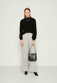 Black long-sleeve top, light gray wide-leg trousers, and a black textured handbag. Pointed black heels complete the outfit.