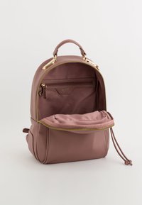 Rucsac roz din piele, cu un design rotund, accesorii aurii și închidere cu fermoar. Interiorul include un buzunar cu fermoar și un compartiment încăpător.