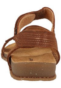 Hnědé kožené sandály s širokými pásky, texturovanou stélkou a plochou, tvarovanou podrážkou. Disponují syrovými okraji a měkkou podšívkou.