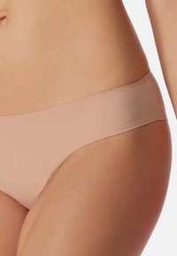 Nude-farvede sømløse bikini-trusser med en blød, glat tekstur, elastisk talje og minimale synlige sømme for komfort.