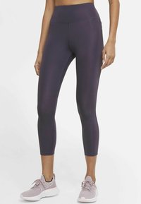 Leggings violets taille haute en matériau extensible, présentant un design élégant, une coupe ajustée et des détails de couture visibles.