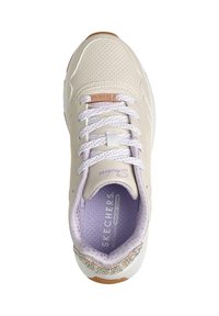 Zapatilla beige con parte superior de malla, detalles en color lavanda, cordones blancos y un adorno de gema decorativa en el lateral. Plantilla de espuma viscoelástica visible.