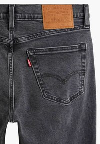 Jeans in denim grigio scuro con etichetta in pelle, cuciture distintive sulla tasca posteriore e un piccolo logo rosso sulla cucitura laterale.