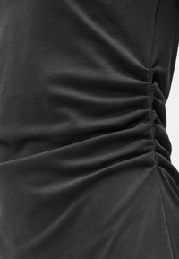 Σκούρο γκρι ύφασμα με μαζεμένη υφή, που διαθέτει λεπτομέρειες ρυτίδωσης στο πλάι. Ομαλή εμφάνιση με απαλό, ελαστικό άγγιγμα.