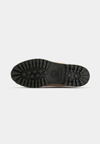 Semelle en cuir marron avec des rainures profondes, dotée d'une base en caoutchouc noir et d'un logo de marque au centre. Motifs de traction détaillés pour une meilleure adhérence.