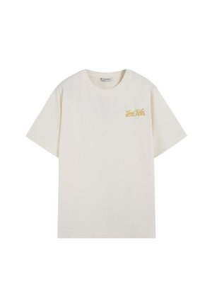 Camiseta de color crema con manga corta, cuello redondo y pequeño texto dorado "Good Vibes Scalpers" en el pecho izquierdo.