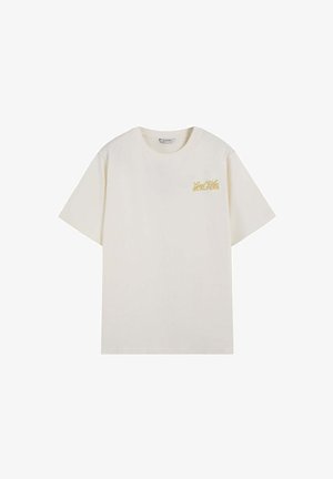 Camiseta de color crema con manga corta, cuello redondo y pequeño texto dorado "Good Vibes Scalpers" en el pecho izquierdo.