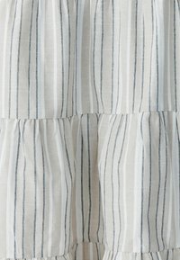 Beige and white striped fabric with vertical navy and white thin lines and gathered ruffle details.