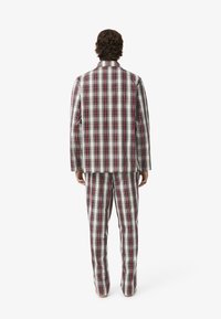 Kockás öltöny szett fehér, bordó és zöld színekben. Tartalmaz egy hosszú ujjú, gombos zakót és a hozzá illő egyenes szárú nadrágot.