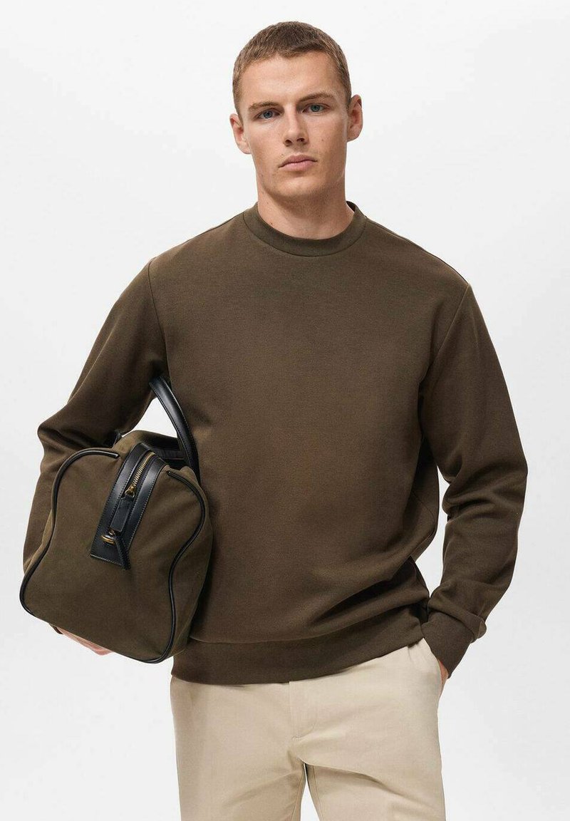 Bruine sweatshirt met een ronde hals, gecombineerd met een gestructureerde groene tas met zwarte accenten en een rits, gepresenteerd tegen een witte achtergrond.