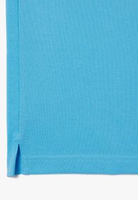 Tecido azul brillante con una superficie texturizada, que presenta un dobladillo limpio y una pequeña abertura en el borde. Ideal para ropa casual o accesorios.