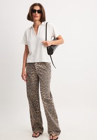 Balta polo krekla, īsas piedurknes, vaļīgs piegriezums; leopardu raksta platās kājas bikses; melni aksesuāri; saulesbrilles; gludas auduma tekstūras.