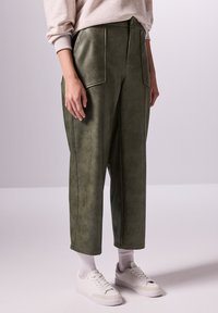 Olivgröna faux läderbyxor med två framfickor, hög midja och raka ben, kombinerat med vita sneakers och ankelsockor.