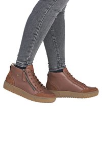 Braune hochwertige Sneakers aus Leder mit einem seitlichen Reißverschluss, runder Zehenpartie und strukturiertem Obermaterial. Gummisohle mit leicht braunem Profil.