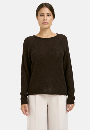 Brauner gestrickter Pullover mit Rautenmuster, kastiger Passform, gerippten Manschetten und rundem Ausschnitt, kombiniert mit hellen, weiten Hosen.